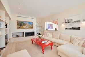 Una sala moderna con una mesa de centro roja, un sofá color beige y una chimenea.