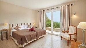 Une chambre à coucher avec un lit, deux tables de chevet, une chaise, une lampe et une vue par la fenêtre.