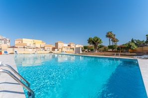 Une piscine à l’eau d’un bleu limpide, entourée de chaises longues et de parasols.