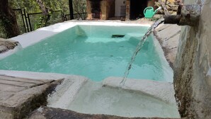 A rectangular pool with clear water, a stone border, and a rustic stone wall in the background. - Country House 'Los Angostones' with Mountain View, Pool and Air Conditioning (Villanueva Del Arzobispo)