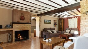 A cozy living room with a fireplace, a sofa set, a coffee table, and a lamp. - Country House 'Los Angostones' with Mountain View, Pool and Air Conditioning (Villanueva Del Arzobispo)
