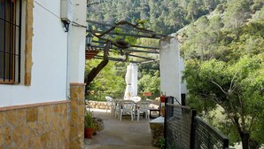 A stone-walled patio with outdoor furniture, a pergola, and a view of a forested hillside. - Country House 'Los Angostones' with Mountain View, Pool and Air Conditioning (Villanueva Del Arzobispo)