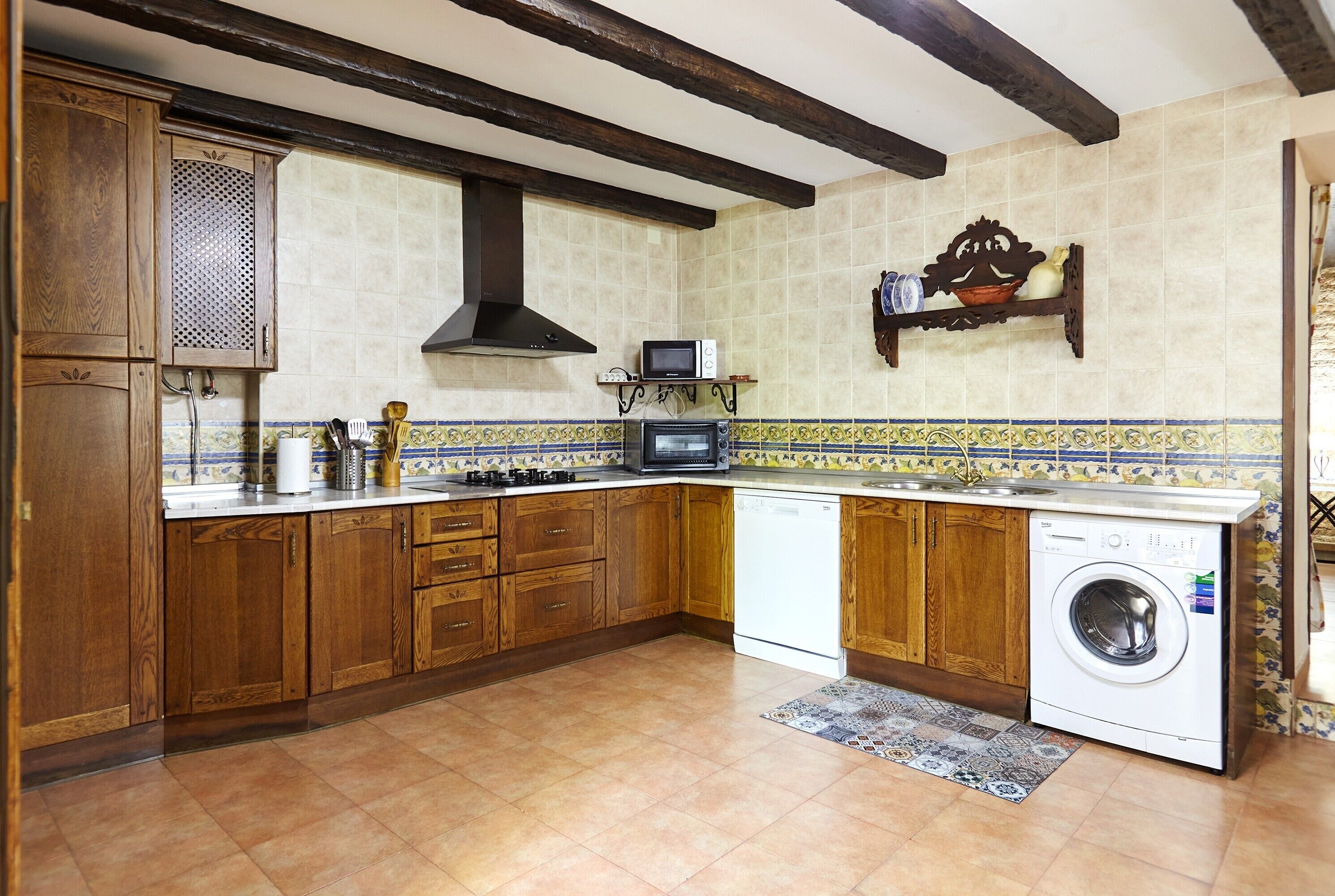 Una cocina con armarios de madera, microondas, estufa y lavadora.