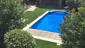 A backyard with a swimming pool, a patio area, and surrounding greenery. - Villa de Luxe à Begur Vue Mer with Sea View, Wi-Fi and Air Conditioning (Sa Riera)