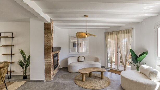 A modern living room with a fireplace, a round wooden table, a sofa, and a hanging light fixture. - Villa de Luxe à Begur Vue Mer with Sea View, Wi-Fi and Air Conditioning (Sa Riera)