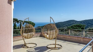 A balcony with two wicker swing chairs, a clear view of the sea, and a mountainous landscape. - Villa de Luxe à Begur Vue Mer with Sea View, Wi-Fi and Air Conditioning (Sa Riera)
