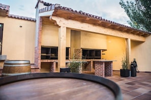 Un patio al aire libre con una parrilla de ladrillo y un barril de madera.