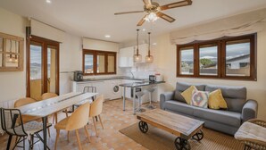 Eine moderne Küche mit Essbereich, einer Couch und einem Deckenventilator.