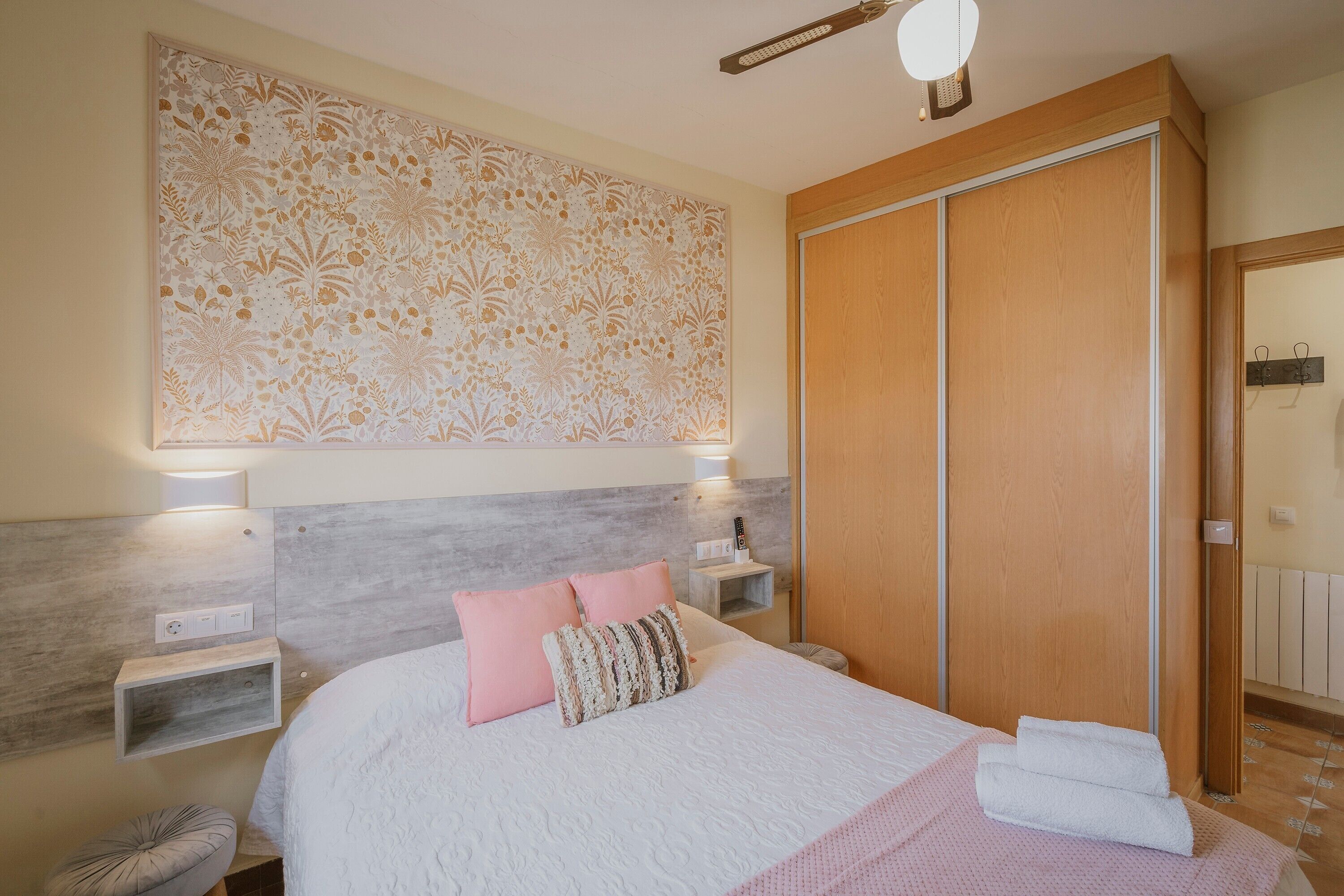 Un dormitorio con cama, mesitas de noche, armario y un panel decorativo en la pared.