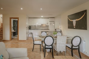 A modern living room with a dining area, kitchen, and staircase.