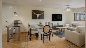 Una sala de estar moderna con comedor, un televisor de pantalla plana en la pared y un ventilador de techo.