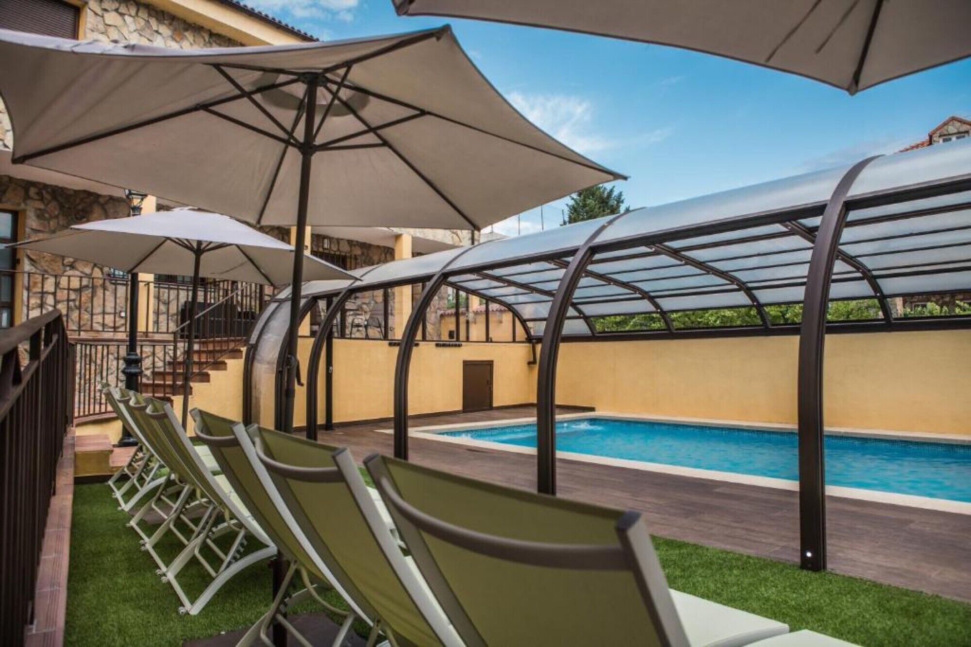 Un área de piscina con sillones de descanso y sombrillas.