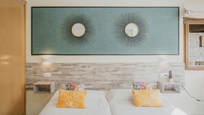Une chambre d’hôtel avec deux lits, un grand miroir fixé au mur et un mur décoré d’un motif imitant la pierre.