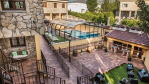 A pool area with a glass enclosure, outdoor seating, and a stone wall.