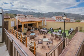 An outdoor patio area with tables and chairs, a covered seating area, and a view of snow-capped mountains.