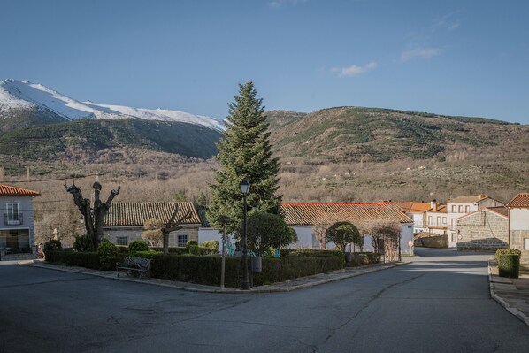 A street with buildings, a bench, and a snow-capped mountain in the background.