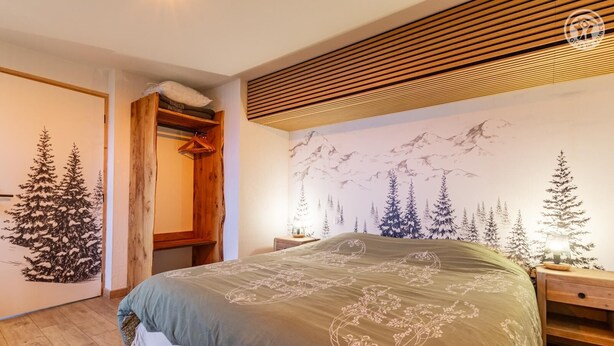 Ein Schlafzimmer mit einem Bett, einem Holzschrank und einer Wandmalerei von Bäumen.