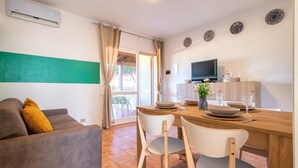 Una sala de estar moderna con un sofá, una mesa de comedor con sillas, un televisor y platos decorativos en la pared.