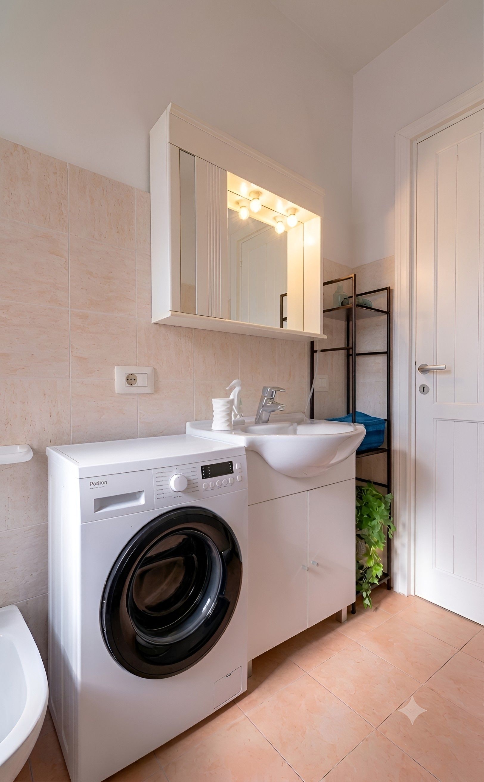 Een moderne badkamer met een wasmachine, een wastafel en een spiegel boven de wastafel.