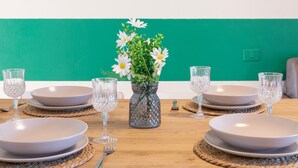 Una mesa de comedor dispuesta con platos, vasos y un jarrón con flores.