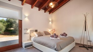 Un dormitorio moderno con una cama grande, mesitas de noche, una lámpara de pie y vistas a través de un ventanal.