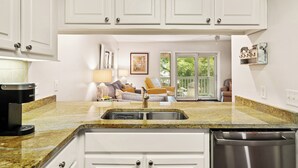 A kitchen with white cabinets, a granite countertop, a stainless steel sink, and a dishwasher. - Steps Away from the Pool, Beach, Restaurants, Village, and Pier! (Saint Simons Island)