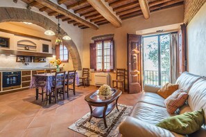 A spacious living area with a dining table, sofa, and kitchen in the background.