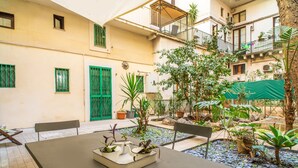 Une cour avec une table, des chaises, des plantes en pot et une porte verte.