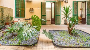 Une cour intérieure agrémentée de plantes en pot, dotée d’un sol carrelé et de portes ouvertes donnant sur les pièces.