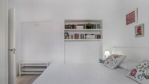 A bedroom with a bed, a bookshelf, a nightstand, and a door.