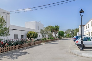 A street with white buildings, a wooden fence, and parked cars. - Holiday Home 'Casa Tahivilla' with Private Terrace, Private Garden and Wi-Fi (Tahivilla)
