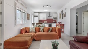 A modern living room with a sofa set, a coffee table, and a kitchen in the background.