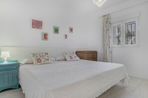 A bedroom with a bed, a nightstand, a dresser, and a window with curtains. - Holiday Home 'Casa Tahivilla' with Private Terrace, Private Garden and Wi-Fi (Tahivilla)