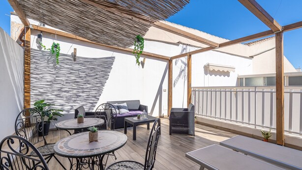 Un patio al aire libre con una mesa, sillas, un sofá y plantas colgantes.