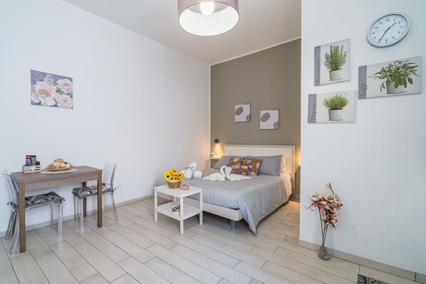 A bedroom with a bed, bedside table, and a wall clock.