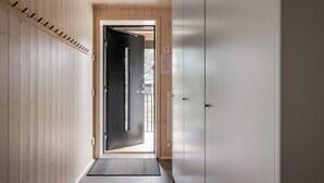 A hallway with wooden walls, a black door, and a white wardrobe. - Renstråket 2005 by Interhome (Tännäskröket)