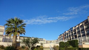 Un bâtiment moderne doté de nombreux balcons, avec un palmier au premier plan.