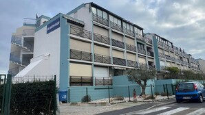 Un immeuble à plusieurs étages, doté de balcons et d’une enseigne indiquant « LE LACTON BLEU ».