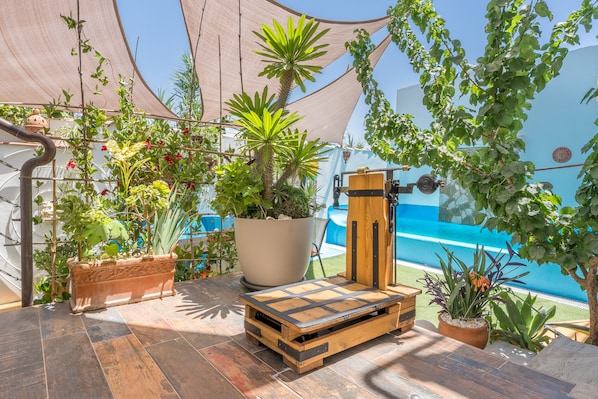 Un patio con plantas en macetas, un banco de madera y vistas a una piscina.
