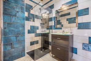 A bathroom with a glass-enclosed shower, a dark wooden vanity, and a mirror above the sink.