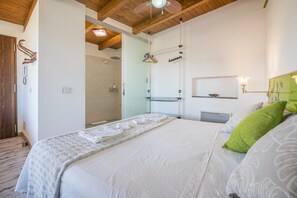 Une chambre à coucher comprenant un lit, une table de chevet, un miroir et un luminaire suspendu.