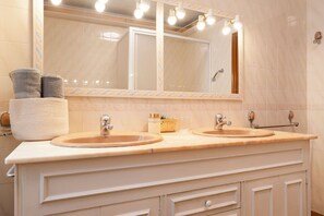 Une salle de bain avec deux lavabos, un grand miroir et un porte-serviettes.