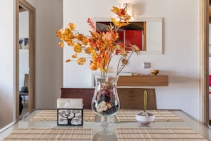 A dining table with a vase of autumn leaves, a candle, and a framed picture.