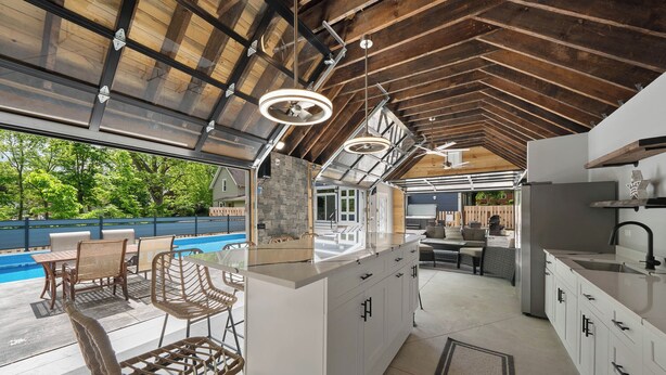 A modern kitchen with a large island, white cabinetry, and pendant lighting.
