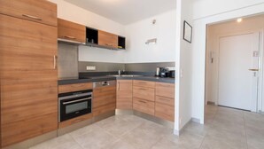 A modern kitchen with wooden cabinets, a built-in oven, and a coffee maker. - 2-Br Seafront Apartment in Cannes (Cannes)