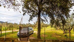 A fenced area with a parked car, trees, and a clear sky. - Room 'Corbezzolo' with Shared Garden and Wi-Fi (Grosseto)