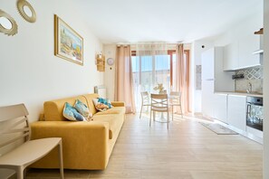 Una sala de estar con sofá, una mesa de comedor y una zona de cocina con estufa.