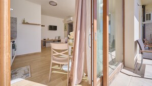 Et moderne interiør med spiseområde, køkken og en skydedør til et udendørs område.