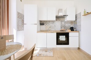 Una cocina moderna con gabinetes blancos, horno empotrado y un salpicadero con diseño.