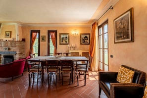 A dining area with a brick fireplace, a table with chairs, and a sofa.
